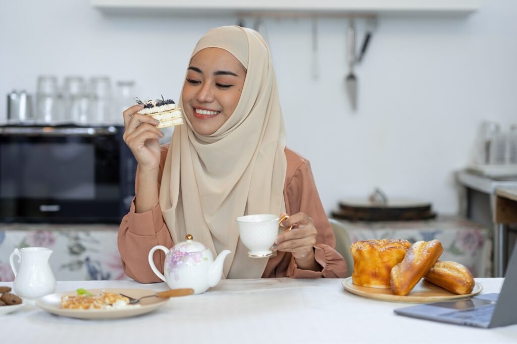 young muslim woman in hijab eating sweets, bread, waffles, cakes, healthy food menu and happily drin