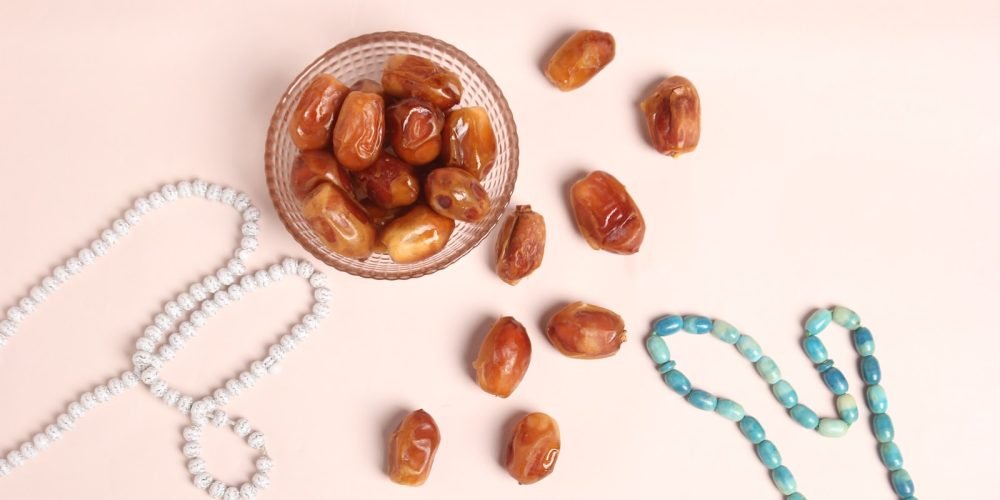 a glass bowl filled with nuts next to a beaded necklace