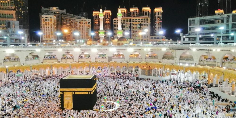 Photo by Hafiz Humayun Khan Aerial view of the Kaaba surrounded by pilgrims in Makkah at night, showcasing a religious gathering.