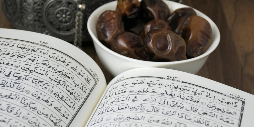 Photo by khats cassim An open Quran with a bowl of dates, symbolizing Ramadan and Islamic traditions.